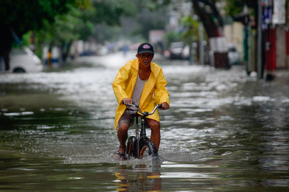 A man on a bicycle wades through a flooded street in Manila, Philippines, July 24, 2021. — Reuters