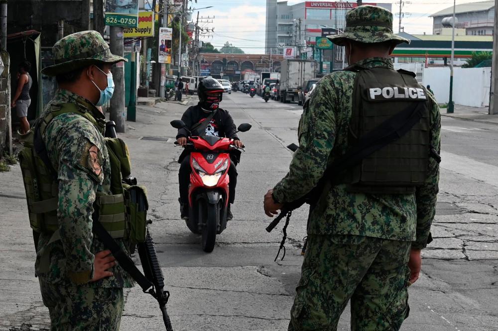 Armed police stop a motorist at a checkpoint as they conduct identity checks during a new round of lockdown measures for the Covid-19 coronavirus outbreak, along a road in Manila on August 4, 2020. — AFP