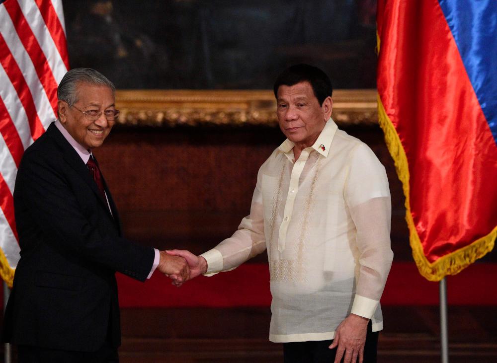 Philippines' President Rodrigo Duterte (R) shakes hands with Malaysia's Minister Mahathir Mohamad after reading their joint statements at the Malacanang Palace in Manila on March 7, 2019. — AFP
