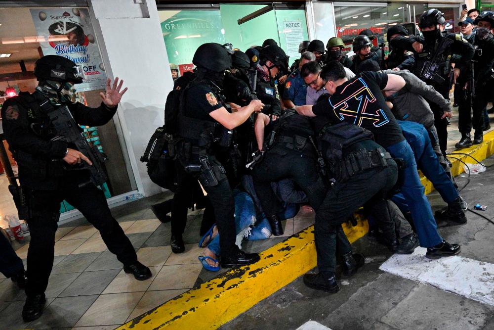 Policemen subdue hostage-taker Archir Paray (obscured) after he surrendered outside a mall in Manila on March 2, 2020. - AFP