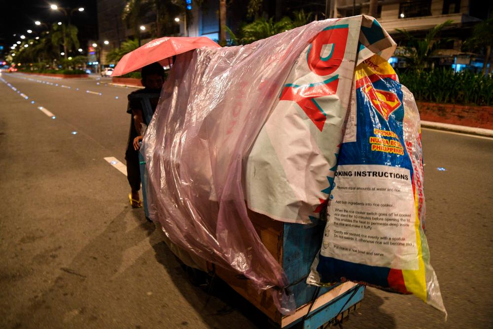 This photo taken on September 14, 2022 shows a homeless man pushing his pushcart ‘home’ as he looks for a place to park for the night along a road in Manila/AFPPix