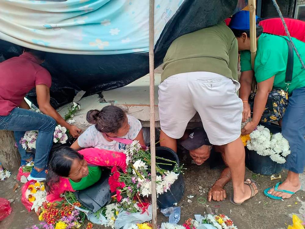 This handout photograph courtesy of Angelo John Jomao-as taken on Dec 15, shows residents attempting to free trapped flower vendors from a portion of a collapsed wall at a public market, after a 6.8-magnitude earthquake struck Padada town, Davao del Sur province on the southern island of Mindanao. — AFP