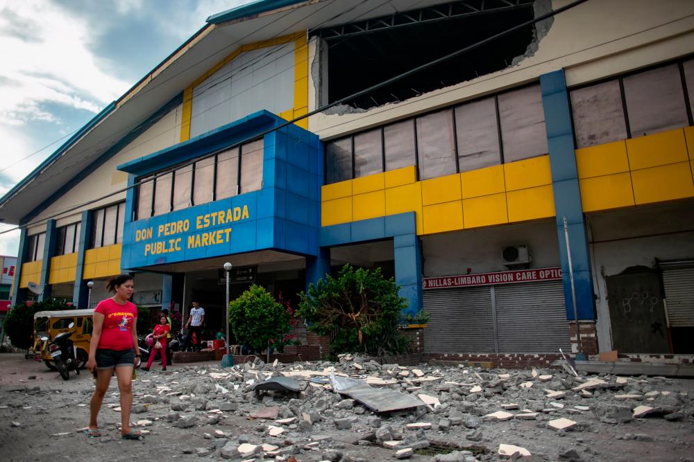 A resident walks past debris from a partially damaged building after a 6.4 magnitude earthquake hit the night before in the city of Digos, Davao del Sur province on the southern Philippine island of Mindanao on Oct 17, 2019. — AFP