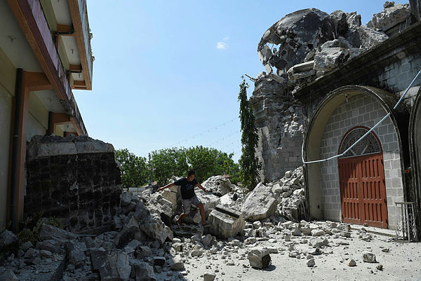 A resident walks past rubble of the 18th century St. Catherine of Alexandria church after its bell tower was destroyed following a 6.3 magnitude earthquake that struck the town of Porac, Pampanga province on April 23, 2019. — AFP