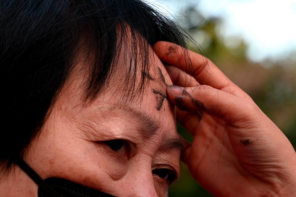 A woman receives ash as she attends a mass in observance of the Ash Wednesday at a church in Manila on February 14, 2024. - AFPPIX
