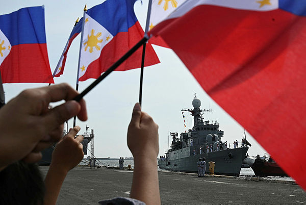 Relatives of Philippine Navy sailors wave their national flags as the navy’s newly-acquired vessel, the Pohang-class corvette BRP Conrado Yap (PS39), docks at the international port in Manila on Aug 20, 2019. — AFP