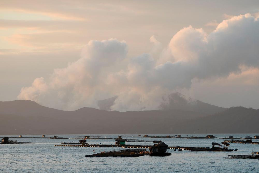 Taal volcano spews steam as fish farms are seen from Laurel town, Batangas province south of Manila on Jan 15. — AFP