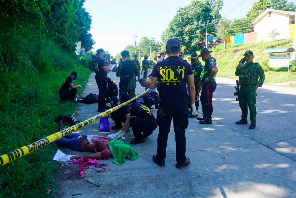 Police gather evidence beside bodies at the scene of a shooting outside a polling station following a confrontation between supporters of rival candidates, during the nationwide village and youth representative elections in Datu Odin Sinsuat town on Mindanao island on October 30, 2023/AFPPix