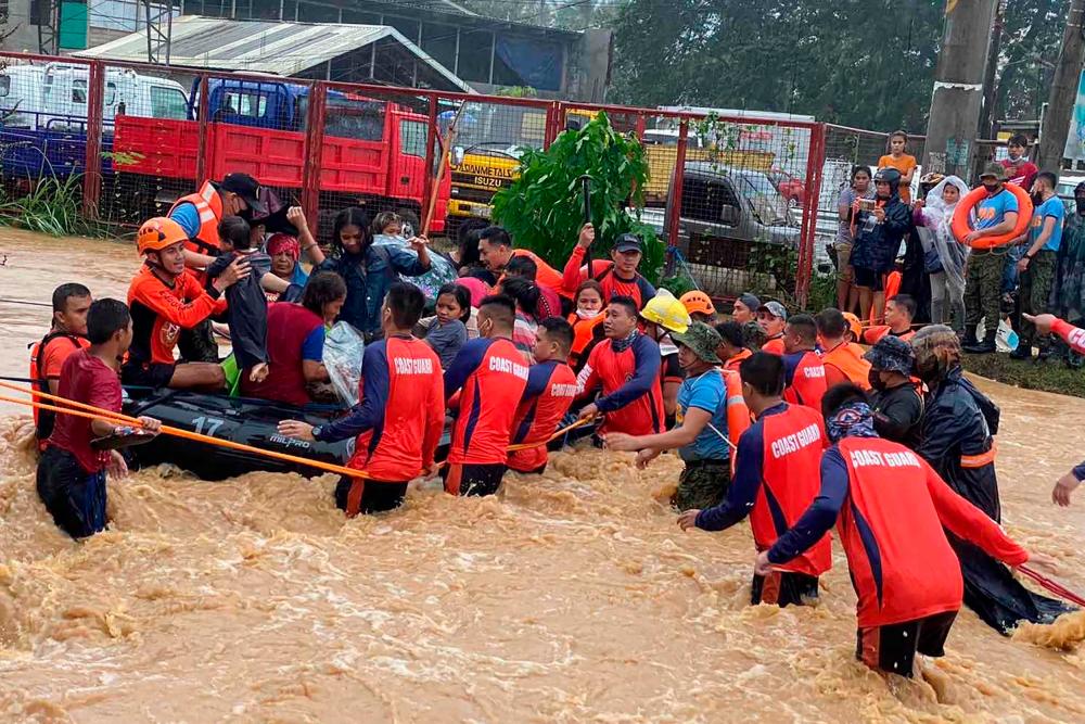 This handout photo taken on December 16, 2021 and received from the Philippine Coast Guard shows rescue workers evacuating residents from their flooded homes amid heavy rains brought by Super Typhoon Rai in Cagayan de Oro City, on the southern island of Mindanao. AFPPIX
