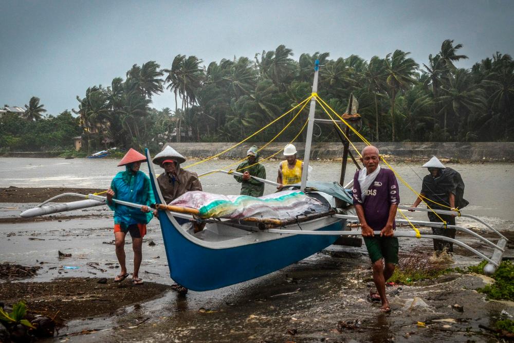 Fishermen carry a boat to higher ground in Baybay, eastern Samar on December 24, 2019, after typhoon Phanfone hit the central Philippines. Typhoon Phanfone smashed into the central Philippines on December 24, ruining Christmas plans as thousands were left stranded at ports or told to leave their homes. - AFP