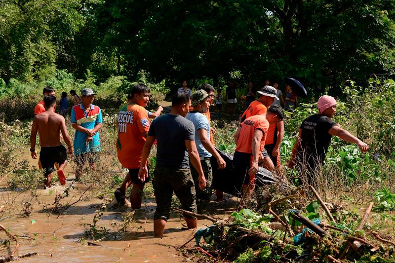 Rescuers and volunteers carry a body bag containing a dead villager found at a flooded area of a village in Tuguegarao, Cagayan province, north of Manila on October 26, 2024. Rescuers in the northern Philippines raced on October 26 to reach people still stranded in areas made inaccessible by flooding from Tropical Storm Trami, which has displaced nearly half a million people and killed at least 87. - JOHN DIMAIN / AFP