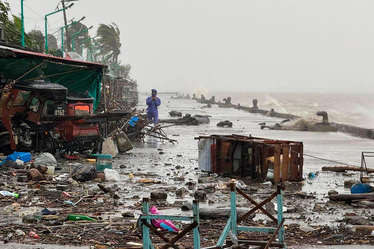 A man stands near debris on a waterfront road amid heavy rain due to weather patterns from Super Typhoon Ragasa in Aparri town, Cagayan province on September 22, 2025. Hundreds of families sheltered in schools and evacuation centres on September 22 as heavy rains and gale-force winds from Super Typhoon Ragasa lashed the northern Philippines and southern Taiwan. (Photo by John Dimain / AFP)