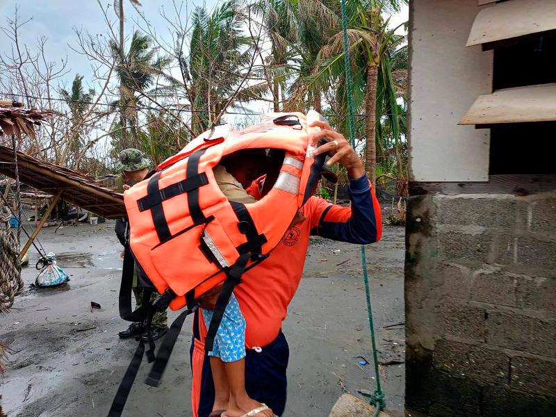 This handout photo taken on November 14, 2024 and released by Buguey Municipal Disaster Risk and Reduction Management Office via Cagayan Provincial Public Information office shows a rescuer carrying a young resident during a forced evacuation operation in Buguey town, Cagayan province, north of Manila, ahead of Super Typhoon Usagi’s landfall. - AFPPIX