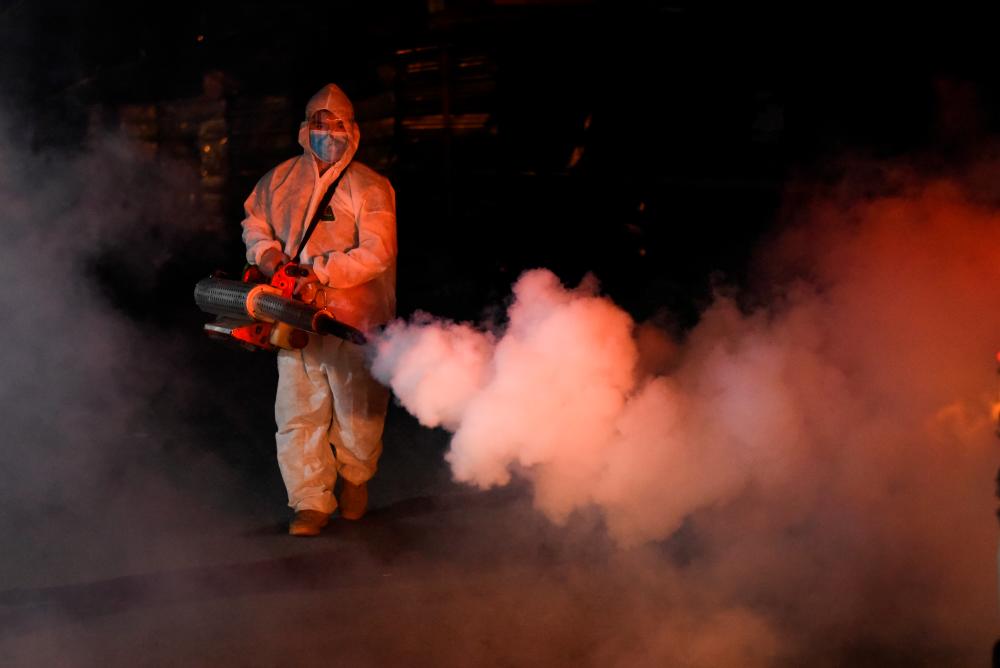 A worker in a hazmat suit disinfects a street as a preventive measure against the spread of the coronavirus disease (Covid-19) at a village, in Manila, Philippines, March 19, 2021. — Reuters