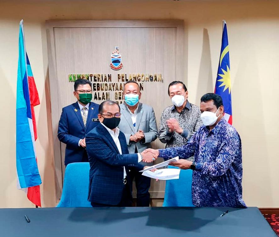 Jumat Idris (front left) and Syed Ali signing the MoU, witnessed by (back row from left) Tourism, Culture and Environment Ministry permanent secretary Datuk Yusrie Abdullah; Sabah Tourism, Culture and Environment Minister Datuk Jafry Ariffin and Tan.