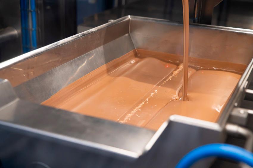 Tempered chocolate is poured into a tray, where it is kept at the ideal temperature and consistency before being molded into bars. $!Tempered chocolate is poured into a tray, where it is kept at the ideal temperature and consistency before being molded into bars.