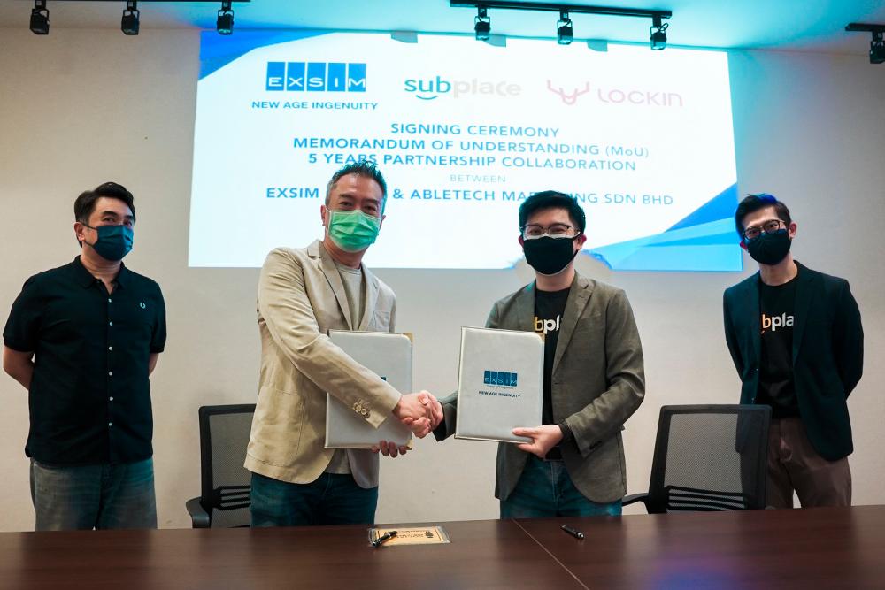 Aik Kiat (second from left) and Mak exchanging documents. Looking on are Aik Hoe (far left) and Subplace head of marketing Ang Siang Wei.