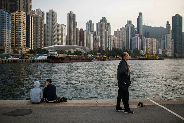 People relax on a public pier next to Victoria Harbour in Hong Kong — AFP