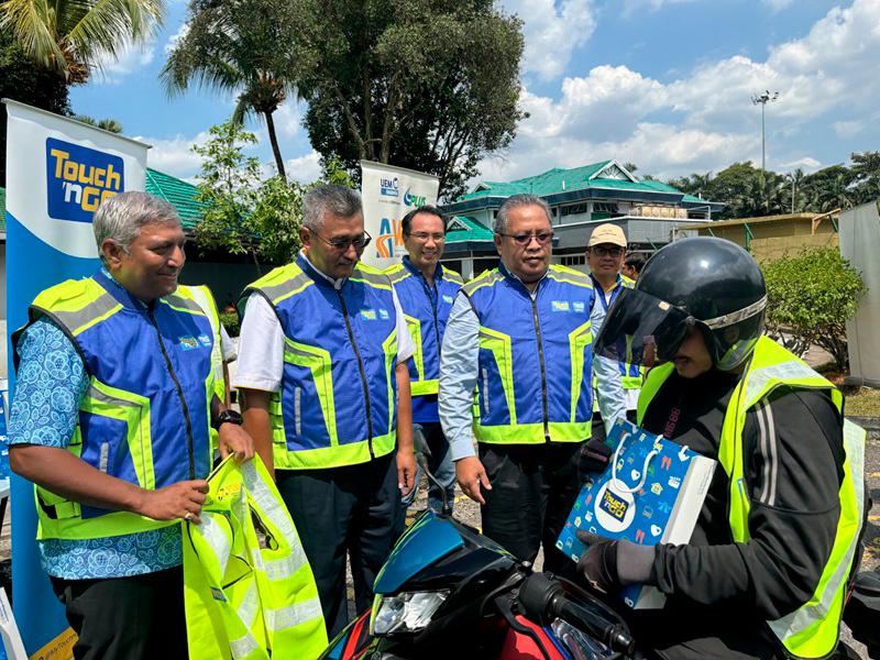 $!Praba, together with Ir Sazali and Zakaria presenting safety vests to motorcyclists during the road safety campaign at the Shah Alam Toll Plaza.