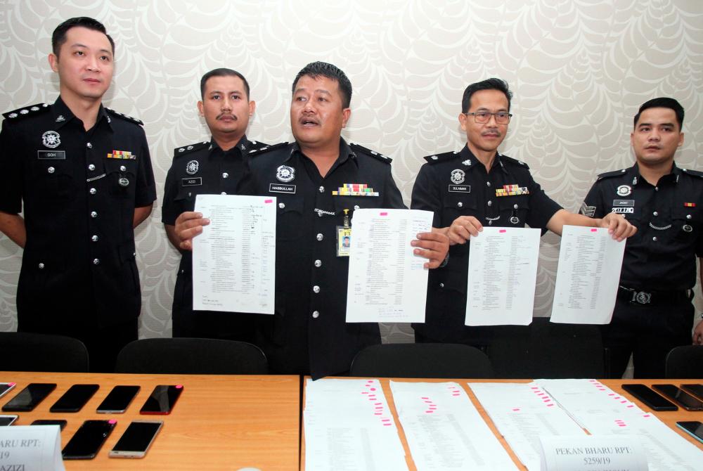 Perak Commercial Crime Investigation Department chief Supt Hasbullah Abd Rahman (C) and other officers show documents containing lists of telephone numbers and victims information during a press conference at the Perak police contingent headquarters today. - Bernama