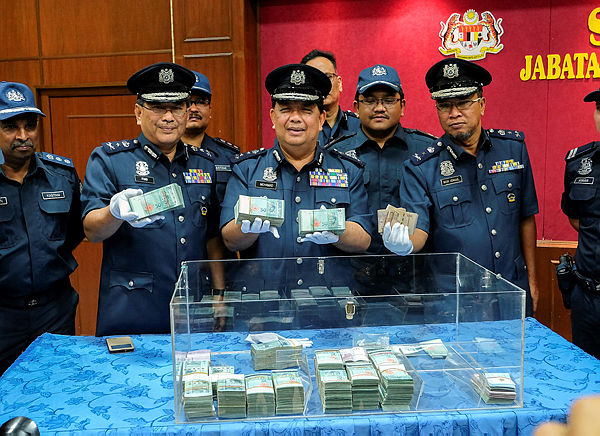 State Customs director Dr Mohamad Saprin (center), shows the curreny notes that were seized from three women at the Pengkalan Hulu Customs branch on Feb 7. — Bernama