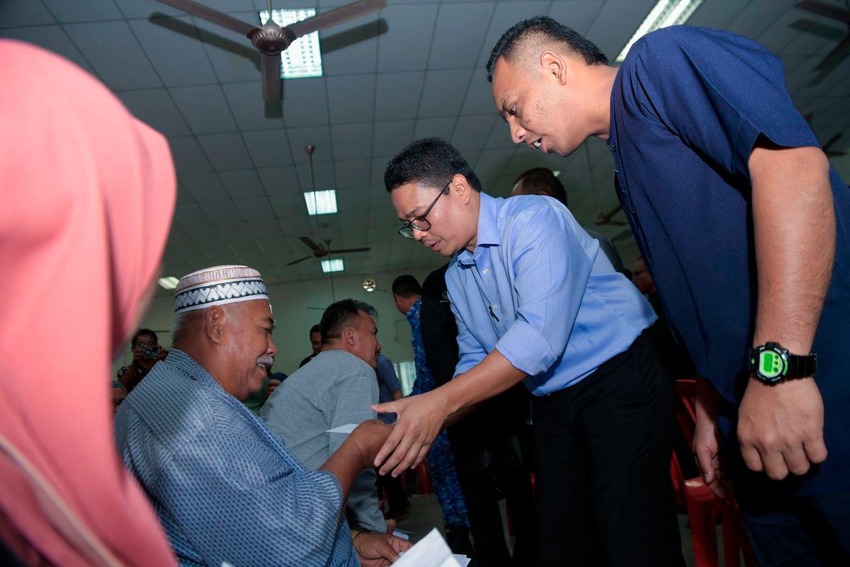 Special Officer to the Menteri Besar for the Kampung Gajah State Legislative Assembly (DUN), Khairul Azwan Harun (second, right), presents aid to recipients at the Perak Tengah District Wang Ihsan Financial Aid Handover Ceremony at the Felcra Seberang Perak Community Hall today. Also present was Pasir Salak UMNO Youth Chief, Mohd Yafiz Mohamad Mustapa (right). - BERNAMA