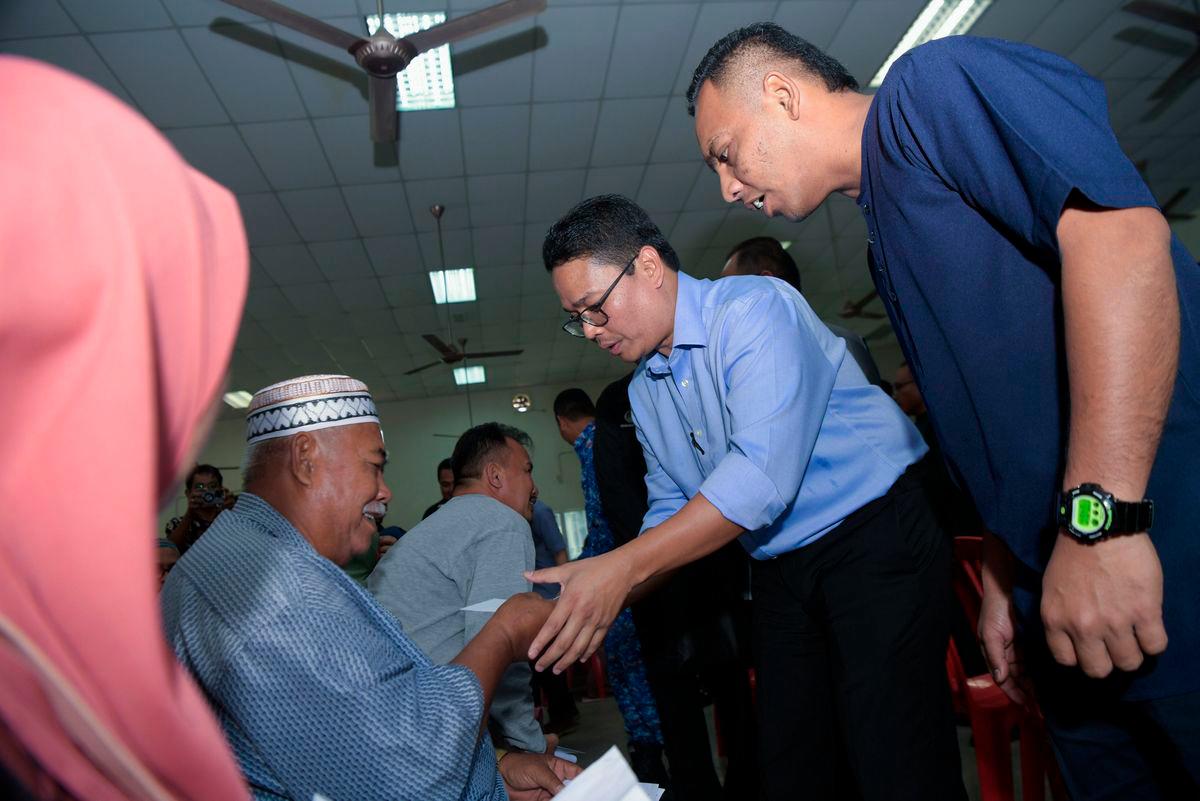Pegawai Khas Menteri Besar Dewan Undangan Negeri (DUN) Kampung Gajah Khairul Azwan Harun (dua, kanan) menyampaikan bantuan kepada para penerima pada Penyerahan Bantuan Wang Ihsan Daerah Perak Tengah di Dewan Orang Ramai Felcra Seberang Perak hari ini - BERNAMA