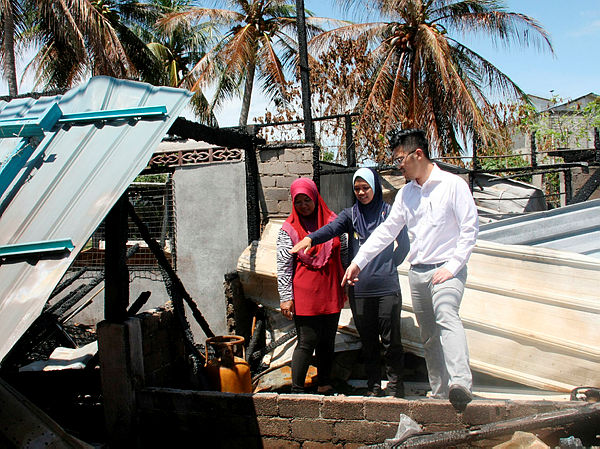 Malaysia Games (Sukma) 2019 handball athlete Nur Fazira Mohd Nor (centre), and her mother Hanisah Din (left), showing the remains of their house that was burnt down to the Perak state Youth and Sports Development Committee chairman Howard Lee Chuan How. — Bernama