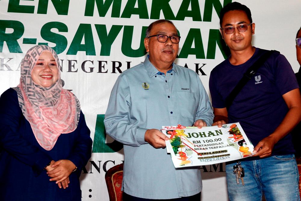 Pengerusi Jawatankuasa Pembangunan Luar Bandar, Perladangan, Pertanian dan Industri Makanan Perak Datuk Zolkafly Harun (tengah) menyampaikan hadiah kepada wakil petani yang berjaya menuai cili merah terpanjang pada majlis perasmian Hari Ladang Daerah Larut Matang dan Selama (LMS) serta Kempen Makan Sayur-Sayuran di pekarangan Pejabat Pertanian LMS/BERNAMApix