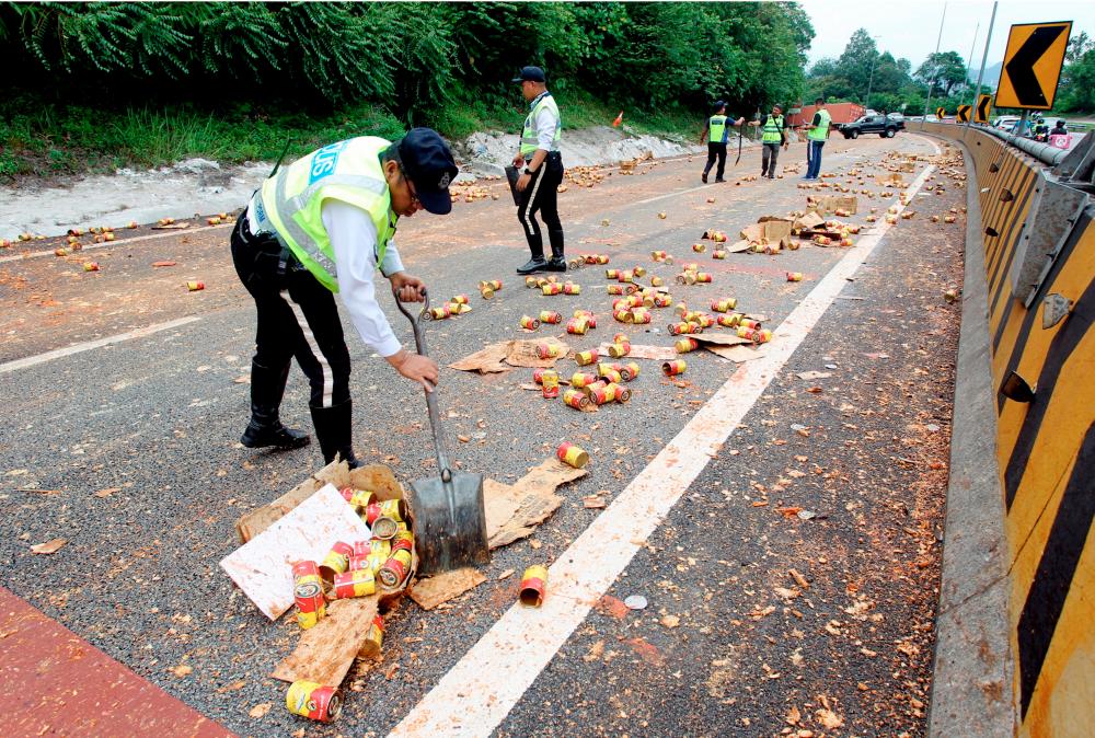 IPOH, 3 August -- Traffic police officers removed cans of sardines scattered on the highway as a result of an overturned lorry accident at KM265.9 of the North-South Highway heading south from the Menora Tunnel this afternoon. BERNAMAPIX