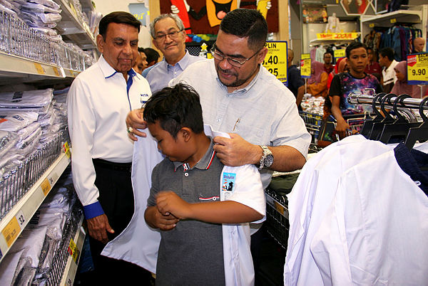 Minister in the Prime Minister’s Department Datuk Seri Dr Mujahid Yusof Rawa helps to put a school shirt on a young boy after a ‘Back To School’ programme at Mydin Mall, Parit Buntar on Dec 8, 2018. — Bernama