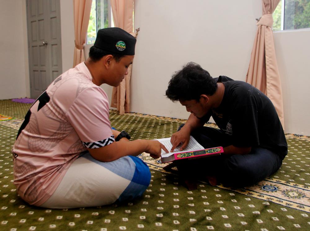 KAMPAR, March 29 -- Maahad Tahfiz Al Quran student Addin Malim Nawar, Muhammad Adzfar Zikri Mastor, 17, (left) helps Amri Alang, 22, study the Quran at Surau Al-Hasanah, Sungai Gapes Indigenous Village, Sahom. BERNAMAPIX