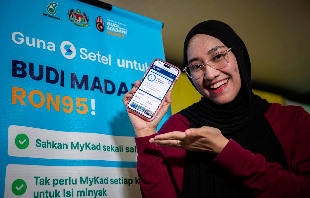 Penerima manfaat BUDI95, Rania Ardini Mohd Asri, menunjukan aplikasi Setel sewaktu menggunakan inisiatif BUDI95 ketika tinjauan di Stesen Minyak di Jalan Sultan Azlan Shah awal pagi ini. - fotoBERNAMA