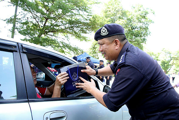 Ipoh police chief ACP A Asmadi Abdul Aziz (right) passing leaflets on road safety to a driver during the ‘Op Selamat’ Road Safety Programme in Ipoh yesterday. — Bernama