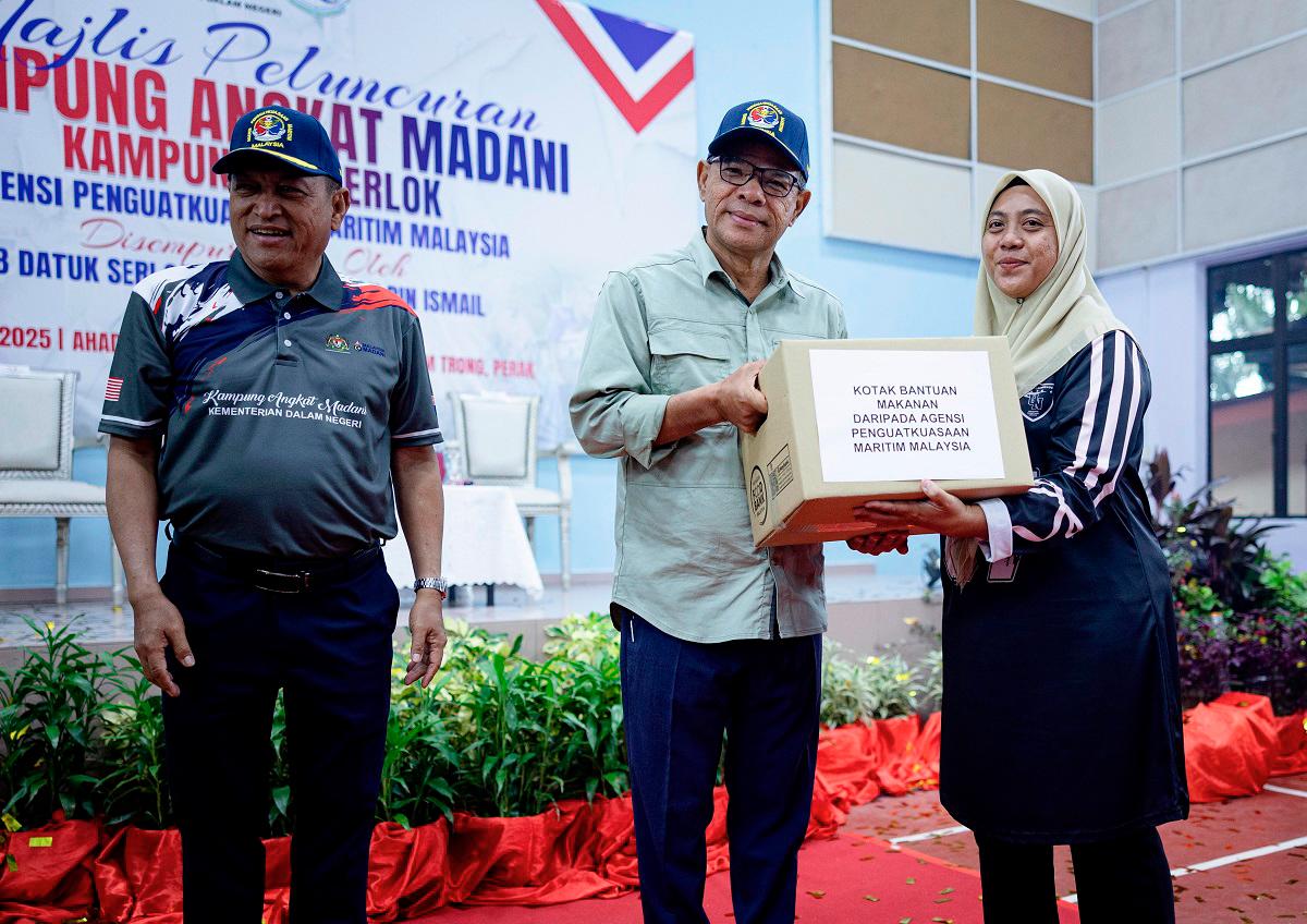 Menteri Dalam Negeri Datuk Seri Saifuddin Nasution Ismail menyampaikan kotak bantuan makanan kepada masyarakat setempat, Roshidah Taha pada Majlis Peluncuran Kampung Angkat MADANI Agensi Penguatkuasaan Maritim Malaysia Tahun 2025 di Dewan Perdana Mukim Trong hari ini. - Bernama