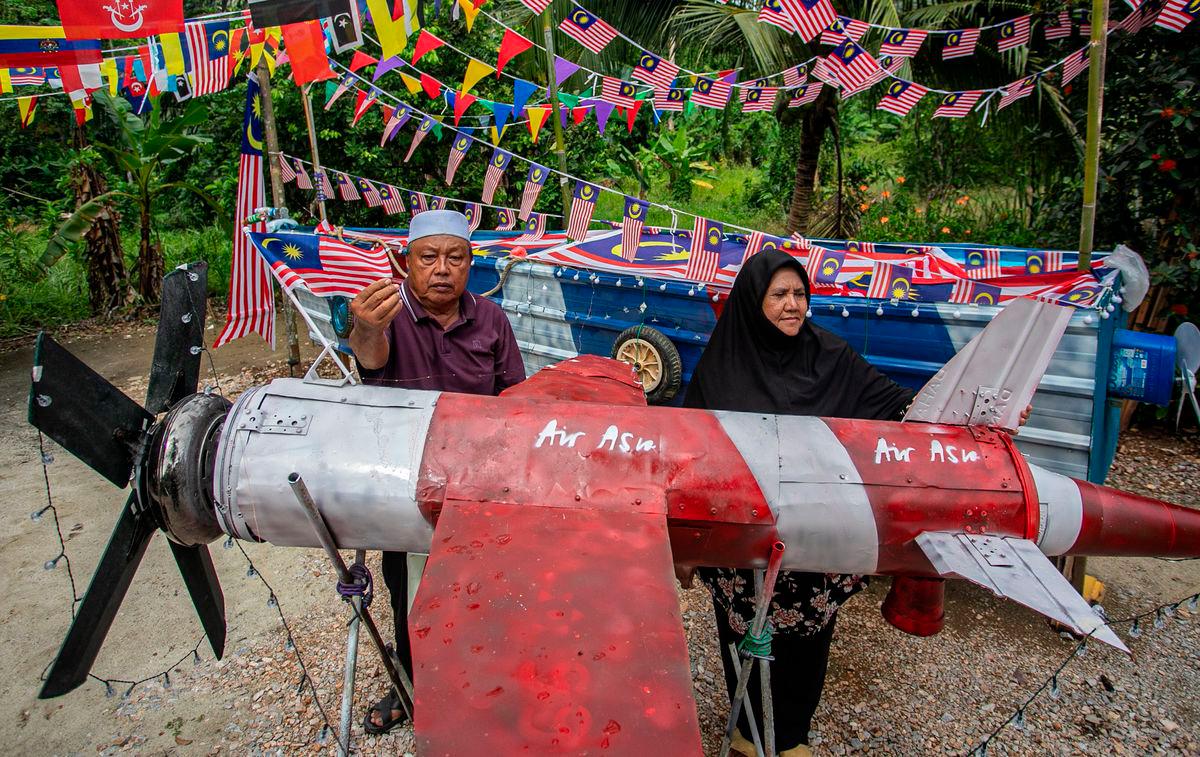 Ahmad Ali Mingan 72 (kiri) bersama isterinya Fauziah Kamarudin 62, menghiasi halaman rumah mereka dengan replika kapal terbang dan sampan yang diperbuat daripada barangan terpakai sempena Program Halaman Rumah Merdeka Peringkat Kampung anjuran pusat perkhemahan dan rekreasi, Gopeng Glamping Park di Kampung Chulek, semalam - fotoBERNAMA