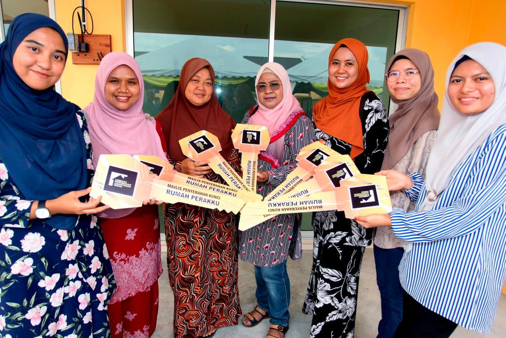 Penerima kunci rumah baharu Nurdiyana Mohd Zarir (kiri) bersama rakan-rakan menunjukkan replika kunci rumah masing-masing pada Majlis Penyerahan Kunci Projek Rumah Perakku, yang disempurnakan oleh Menteri Besar Perak Datuk Seri Saarani Mohamad di Taman Perakku Serdang, hari ini/BERNAMAPix
