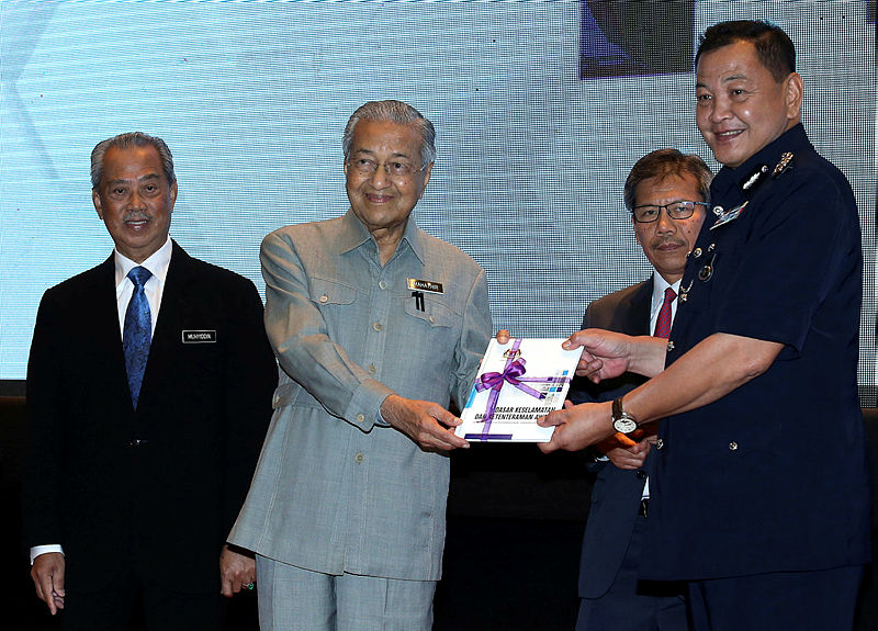 Home Minister Tan Sri Muhyiddin Yassin (L), and Home Ministry Secretary-General Tan Sri Alwi Ibrahim (2nd R), look on as Prime Minister Tun Dr Mahathir Mohamad (2nd L) presents the Security and Public Order Policy (DKKA) policy book to Inspector-General of Police Tan Sri Abdul Hamid Bador (R), at Putrajaya, on Oct 3, 2019. — Bernama