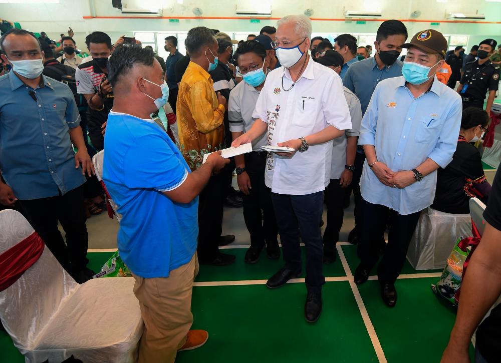 Perdana Menteri Datuk Seri Ismail Sabri Yaakob (tengah) menyampaikan Bantuan Wang Ihsan kepada salah seorang mangsa banjir pada Program Penyerahan Bantuan Wang Ihsan dan Bantuan Bakul Makanan Mangsa Banjir Daerah Pitas hari ini.Turut hadir Ketua Menteri Datuk Seri Hajiji Noor (kanan).-BERNAMAPix