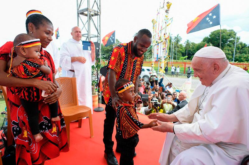 This handout picture taken and released on September 8, 2024 by the Vatican Press Office shows Pope Francis greeting a child during a meeting with Catholic faithful of the diocese of Vanimo in front of Holy Cross Cathedral in Vanimo, Papua New Guinea, on September 8, 2024. - AFP PHOTO / VATICAN MEDIA