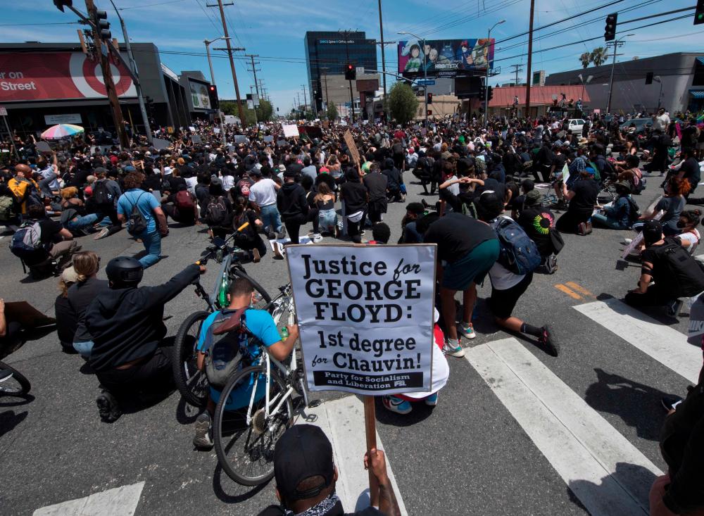 Demonstrators kneel as they block an intersection in the Fairfax District in Los Angeles, California on May 30, 2020 during a protest for death of George Floyd, an unarmed black man who died while while being arrested and pinned to the ground by the knee of a Minneapolis police officer. Demonstrations are being held across the US after George Floyd died in police custody on May 25. - AFP