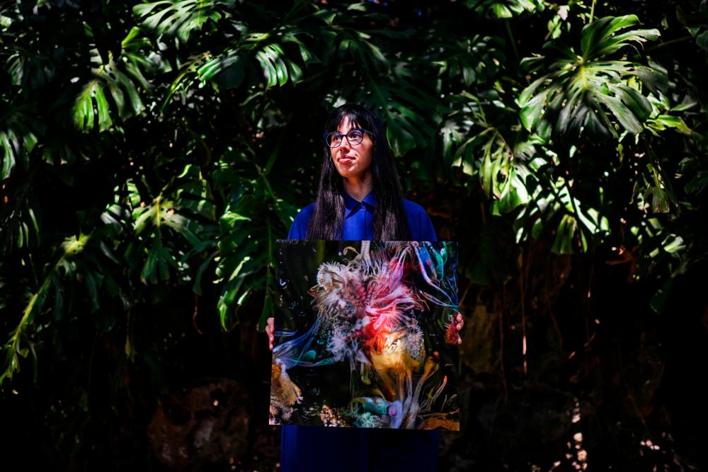 Argentinian artist Sofia Crespo holds one of her works as she poses for a photo at the Estrela garden in Lisbon on June 8, 2022. AFPPIX