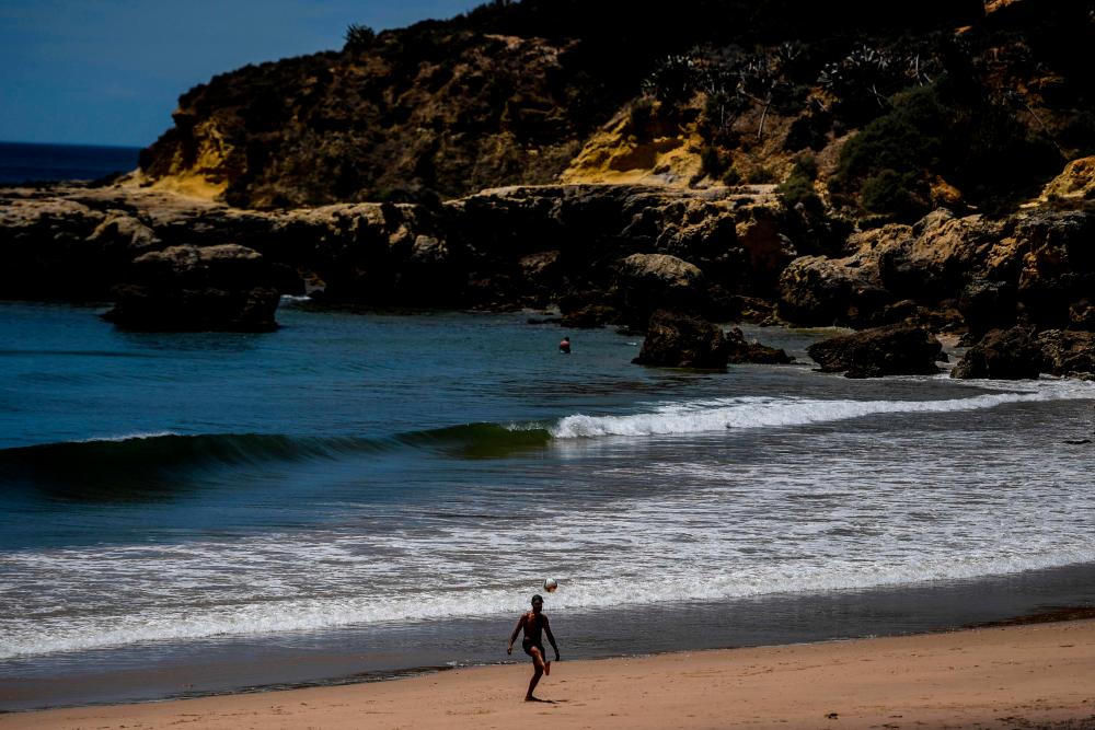 A man plays with a ball at Oura beach, Albufeira, in Algarve, south of Portugal, on May 17, 2021. British holidaymakers returned to Portugal on Monday as the country seeks to revive its battered tourism industry after lifting travel restrictions that had been imposed to curb Covid-19. – AFP