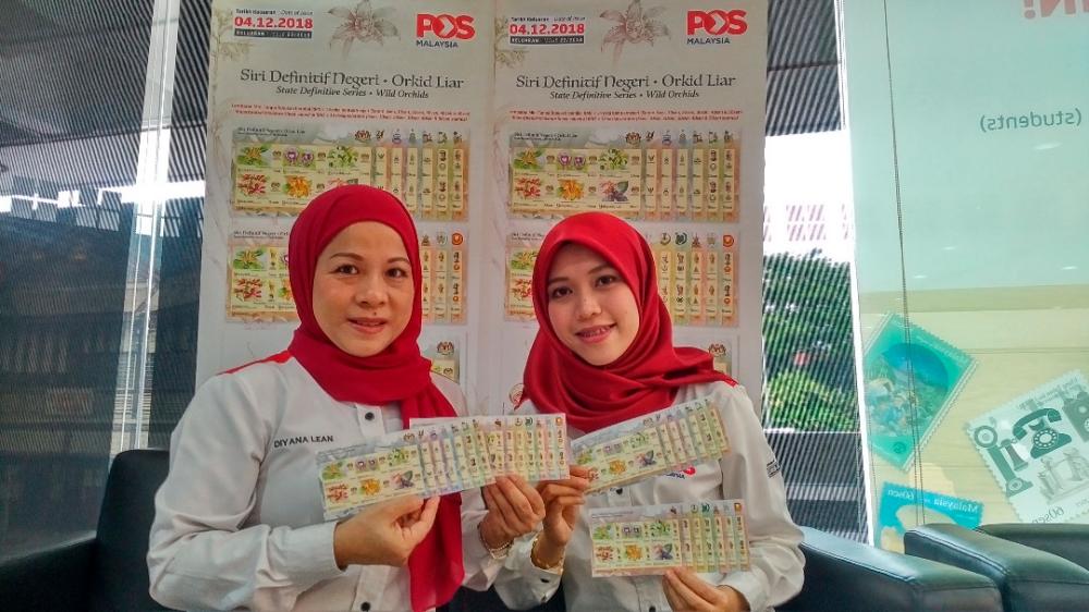 From left: Pos Malaysia Head of Stamp &amp; Philately Unit Diyana Lean Abdullah posing with staff Maizatul Nadhirah Mat Nayan showing the State Definitive series – Wild Orchids stamps.