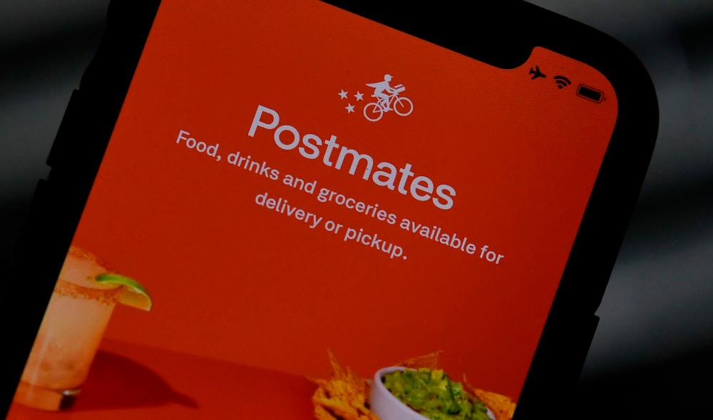 The logo of delivery app Postmates is shown on a smartphone screen. – AFPPIX