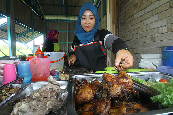 Assistant at the RM1 Wrung, Nooraleya Yazid, 29, cuts up a chicken for the chicken rice meal on their menu yesterday — Bernama