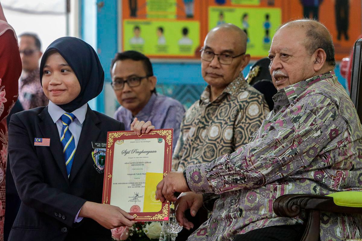 The Raja of Perlis, Tuanku Syed Sirajuddin Jamalullail, graciously presented the Student of the Year Award to Aina Safiyah Ahmad, 17, during the Excellence Award and Co-curriculum Day at SMK Derma for the 2025 Academic Session. Also present were the Menteri Besar of Perlis, Mohd Shukri Ramli (third from left), and the Director of Education for Perlis, Rose Aza Che Ariffin (second from left). - BERNAMA