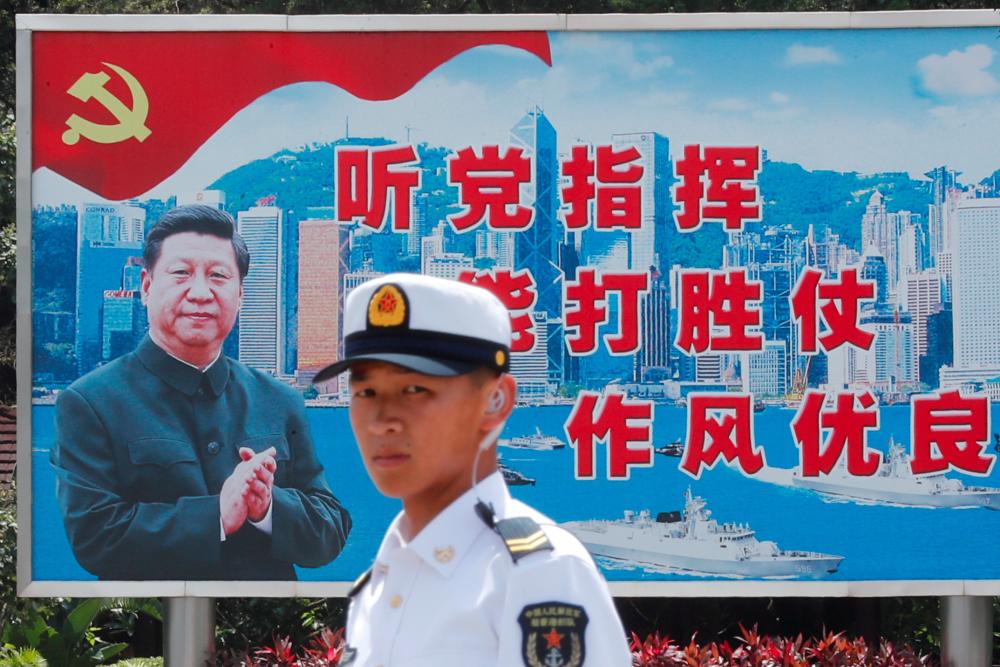 A People's Liberation Army Navy soldier stands in front of a backdrop featuring Chinese President Xi Jinping during an open day of Stonecutters Island naval base, in Hong Kong, China, June 30, 2019. - Reuters
