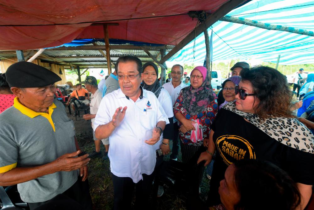 Warisan candidate Datuk Karim Bujang (C) speaks to residents during campaigning for the Kimanis Parliamentary by-election in Kampung Saga-Saga today. - Bernama