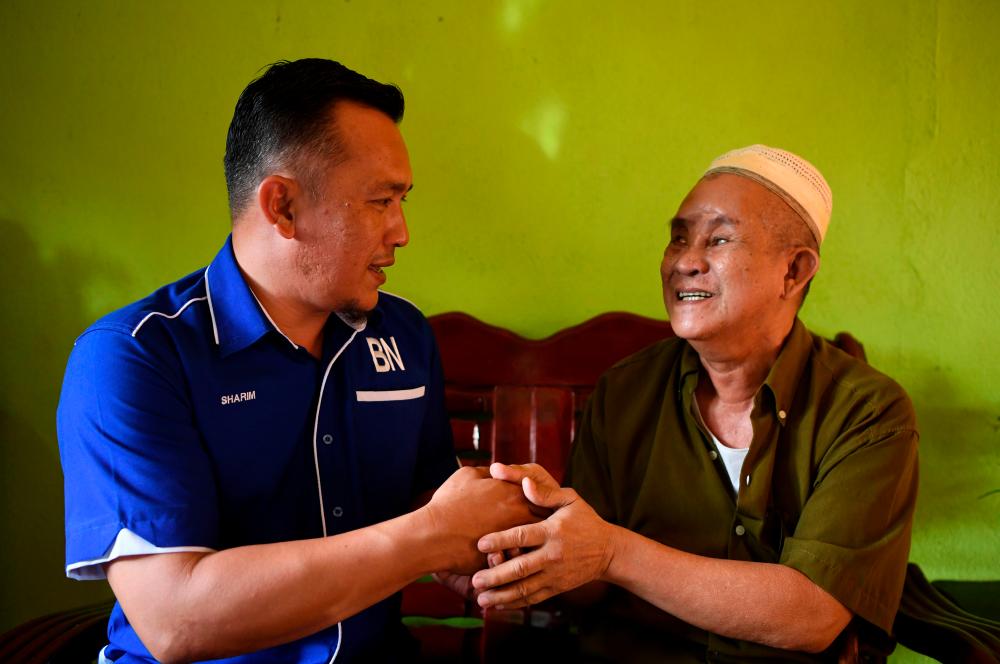 Barisan Nasional’s candidate for the Chini by-election (BN) Mohd Sharim Md Zain (L) greets a Felda settler, Sanosi Sabran, 65, on July 2, 2020. — Bernama